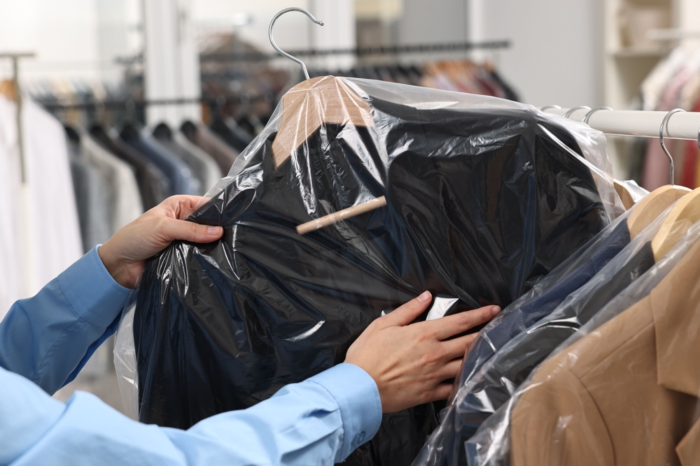Dry-cleaning,Service.,Woman,Taking,Jacket,In,Plastic,Bag,From,Rack